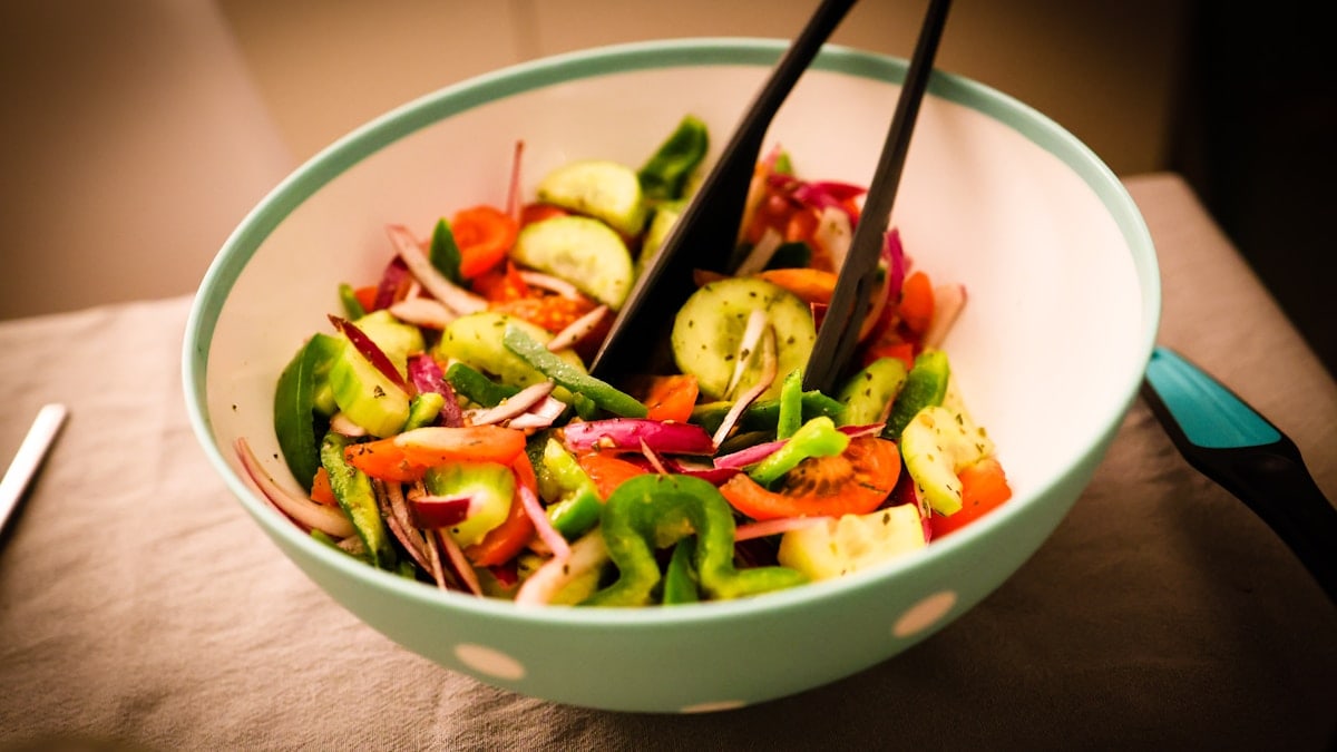 a bowl of mixed vegetables with chopsticks in it